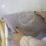 Couverture bébé bio gris violine pliée, tenue par une maman