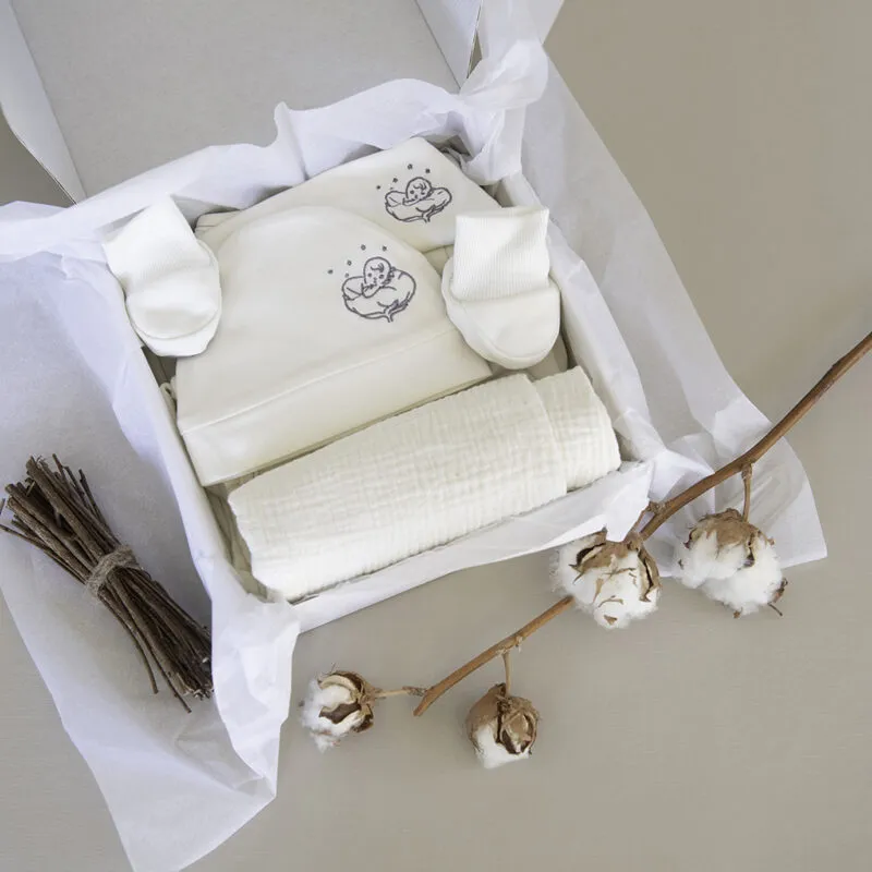 Coffret naissance L'Essentiel ouvert : vêtements bébé en coton bio écru dans sa boîte blanche