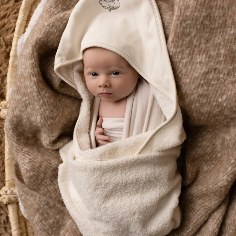 Nouveau-né enveloppé dans une sortie de bain bébé écrue à capuche Bébé Coton