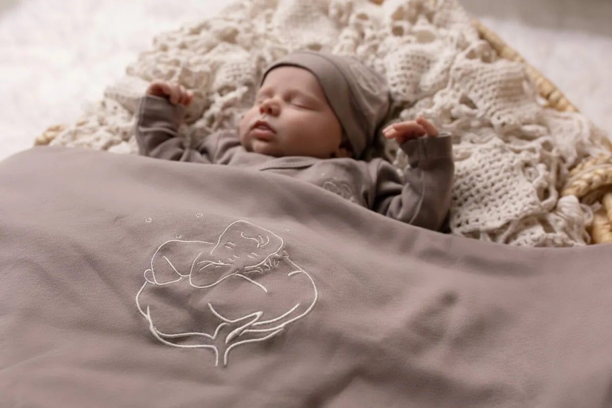 Nouveau-né endormi sous une couverture bébé bio gris violine Bébé Coton