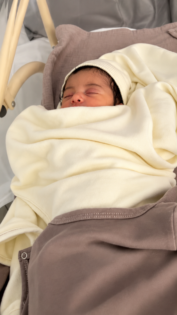 Nouveau-né endormi dans son berceau sous une couverture écrue et taupe Bébé Coton en coton bio